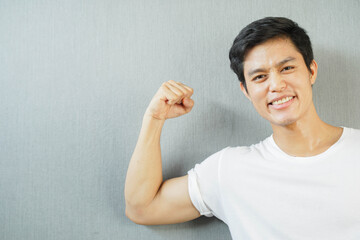 close up young asian man smile with showing bicep forearm to good health and strong body concept