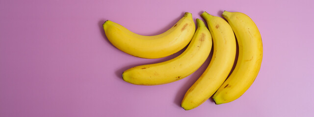 Four real bananas on purple background.