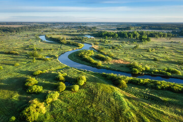 Beautiful panoramic view of winding river surrounded meadow and forest in morning light. Sunrise...