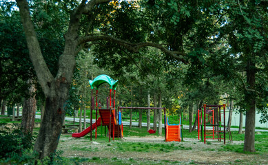 Fototapeta na wymiar Children's play area in the park. Game sports structures made of iron in the yard. Safe beautiful playground for children in the forest.