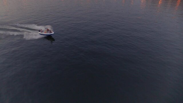 An aerial view of a boat that floats on a river in the city centre at sunset