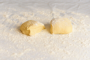 the process of preparing dough for dumplings, rolling out the dough and cutting circles with women's hands to sculpt dumplings on a light kitchen table