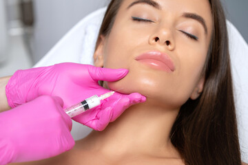 Cosmetologist makes lipolytic injections to burn fat on the chin, cheeks and neck of a woman...
