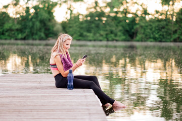 athlete using smartphone after the workout - caucasian fit woman in sportswear using a mobile phone