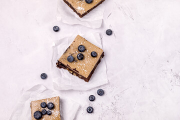 Pieces of Homemade Chocolate Brownies Decorated with Ripe Blueberry on Gray Background Tasty Chocolate Dessert Copy Space