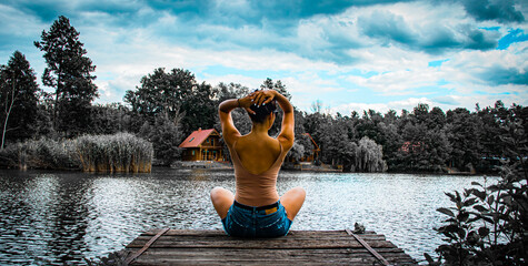 Girl sitting on a lake dock - obrazy, fototapety, plakaty