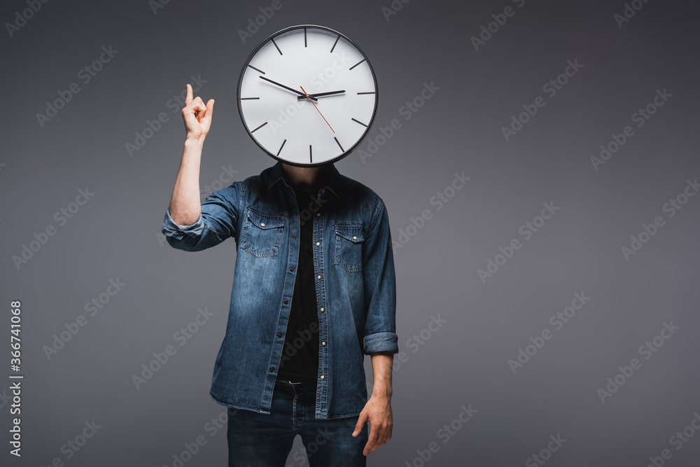 Wall mural man with clock near face pointing with fingers on grey background, concept of time management