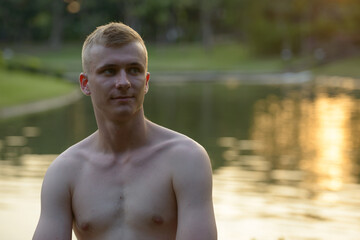 Young man with blond hair shirtless at the park outdoors