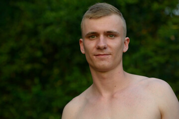 Young man with blond hair shirtless at the park outdoors