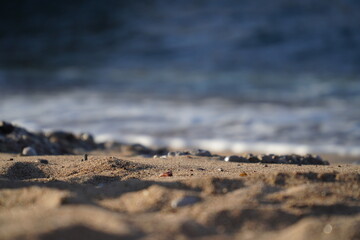 Closeup of sand and pebble on beach during summer afternoon