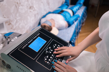 doctor setting up pressotherapy machine for slimming in spa salon