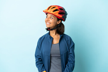 Young cyclist woman isolated on blue background looking side
