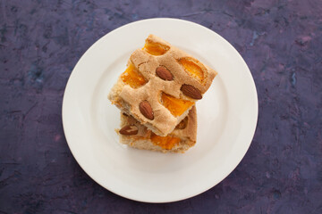 Two pieces of pie with apricot and almond on violet grunge background, view from above
