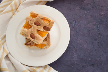 two pieces of pie with apricot and almond in the left side of violet grunge background, view from above

