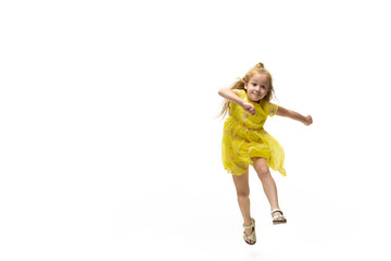 Happy child, little and emotional caucasian girl jumping and running isolated on white background. Looks happy, cheerful, sincere. Copyspace for ad. Childhood, education, happiness concept.