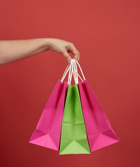 woman holds stack of paper bags on red background, shopping concept