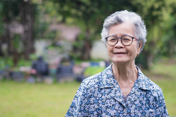 Portrait of an elderly woman wearing eyeglasses looking at camera while standing in a garden