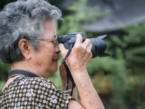 Elderly woman shooting photo by digital camera at garden