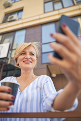 Smiling mature lady taking a selfie outdoors