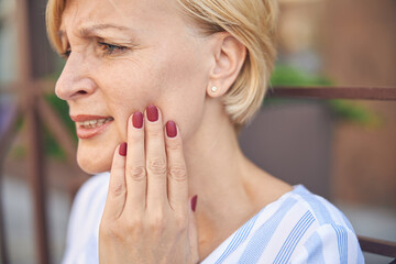 Low-spirited short-haired lady experiencing an acute toothache
