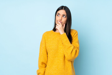 Young caucasian woman isolated on blue background having doubts and with confuse face expression