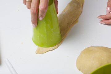 A woman forms dumplings with a glass. Extrudes the required shape in the dough. Cooking dumplings with blueberries and cherries.