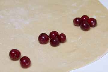 The piled cherries lie on the rolled out dough. Cooking dumplings.