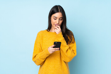 Young caucasian woman isolated on blue background thinking and sending a message