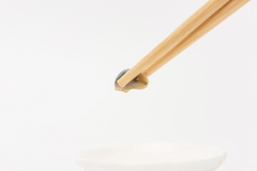 A pair of chopsticks to pick up a yellow mud snail.