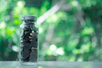 Thai coins in glass jar  on blur nature background