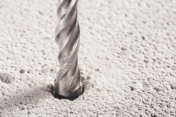metal drill bit make holes in concrete wall on industrial drilling machine with shavings. Metal...