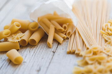 a lot of different kinds of egg noodles and yellow pasta on wooden background