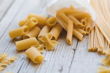 a lot of different kinds of egg noodles and yellow pasta on wooden background