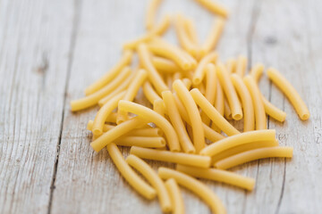 a lot of different kinds of egg noodles and yellow pasta on wooden background