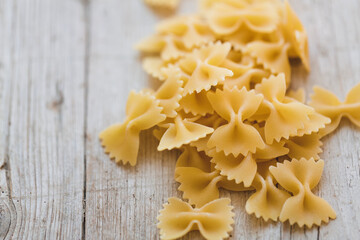 a lot of different kinds of egg noodles and yellow pasta on wooden background