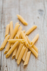 a lot of different kinds of egg noodles and yellow pasta on wooden background