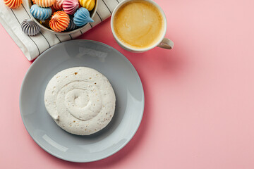 White meringue cookie on pink background with colorful mini meringues