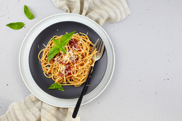 Classic Italian pasta with tomato sauce,  parmesan and basil on a plate on a light background. Top view, copy space