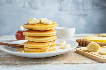 Fototapeta na wymiar Pancakes topped with honey and bananas on the table