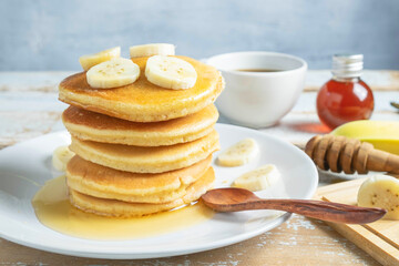 Fototapeta na wymiar Pancakes topped with honey and bananas on the table