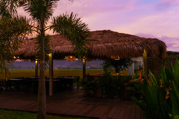 Fototapeta na wymiar Beautiful pink sunset in the tropics. Street canopy from hay, kitchen area with rice field view