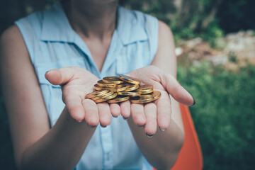 Female hands holding gold coins coins outdoor background.