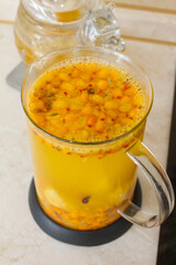 Vitamin useful sea buckthorn tea in a glass teapot with fresh sea buckthorn berries, orange, cinnamon sticks and honey. The concept of rest, relaxation. top view with a copy of the space