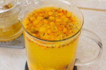 Vitamin useful sea buckthorn tea in a glass teapot with fresh sea buckthorn berries, orange, cinnamon sticks and honey. The concept of rest, relaxation. top view with a copy of the space