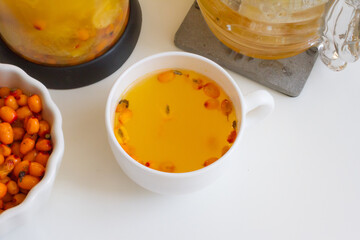 Vitamin useful sea buckthorn tea in a glass teapot with fresh sea buckthorn berries, orange, cinnamon sticks and honey. The concept of rest, relaxation. top view with a copy of the space