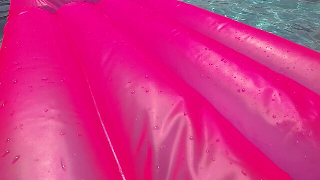 A pink rubber mattress runs through the frame, the camera stays in the pool