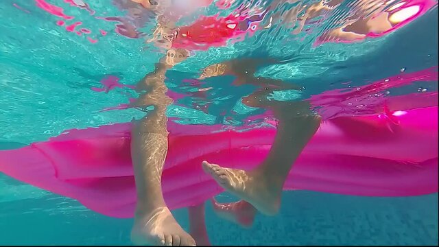 Two girls on a rubber mattress / two girls sit on a rubber mattress in the pool and talk, underwater shot
