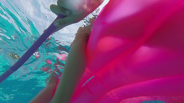 Two girls on a rubber mattress / two girls sit on a rubber mattress in the pool and row, underwater shot