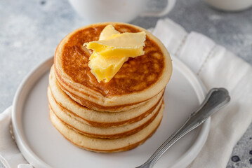 Stack of american pancakes with butter on light concrete background for breakfast.Close up