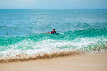 Sexy slim girl riding on surf board in the ocean. Healthy active lifestyle in summer vocation.
